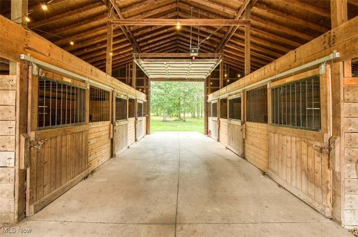 Inside the barn, looking down the aisle past the stalls to the field beyond